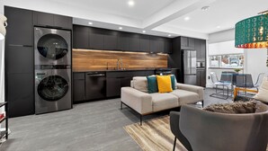 Een moderne keuken met inbouwapparatuur, een wand met houten accenten en een eethoek met een tafel en stoelen.