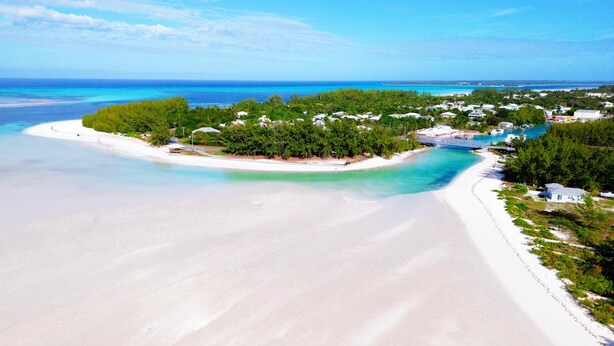 A coastal resort with a sandy beach, lush greenery, and clear turquoise waters.