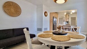 A modern dining area with a round table, white chairs, and woven placemats.