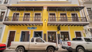 A yellow building with a sign reading "OraBoi" and a sign for "Pierce Tatti". - Soho House The Grand Patio (San Juan)