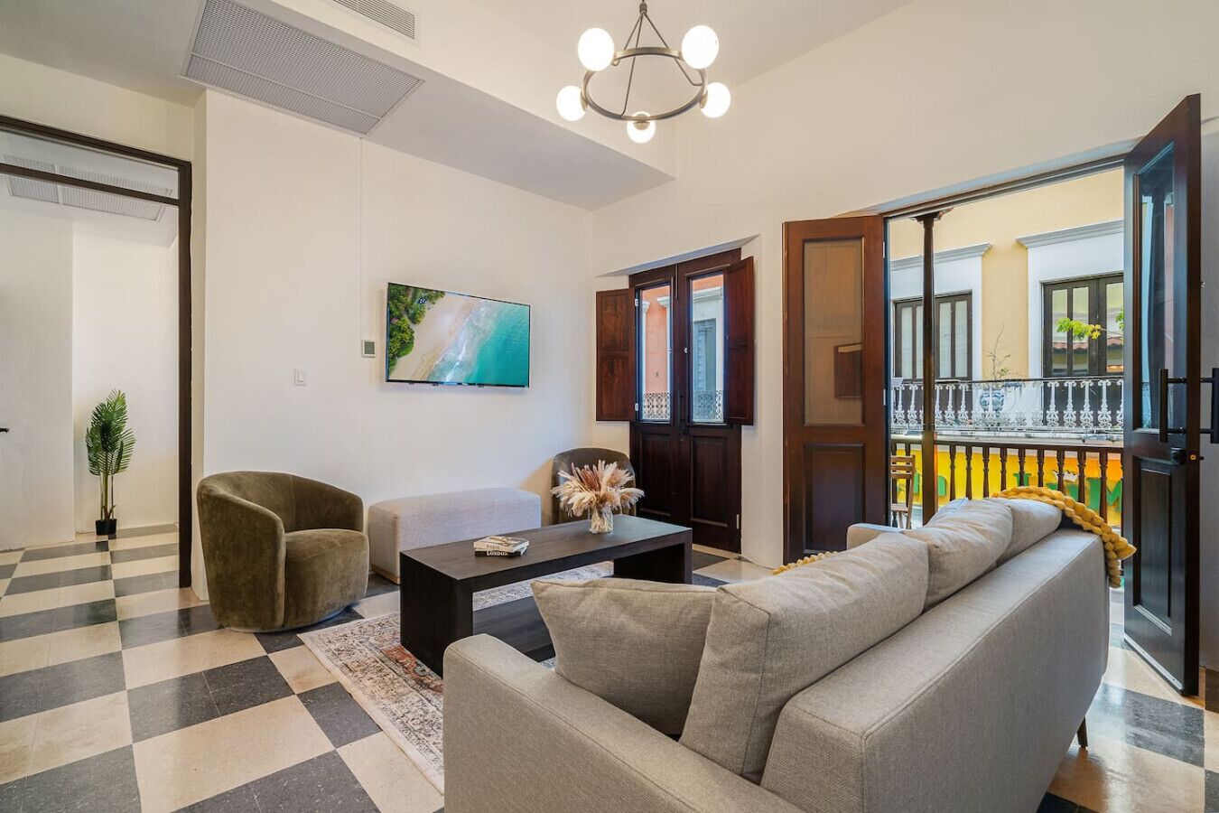 Uma sala de estar com um sofá, poltronas, uma mesa de centro e uma televisão.