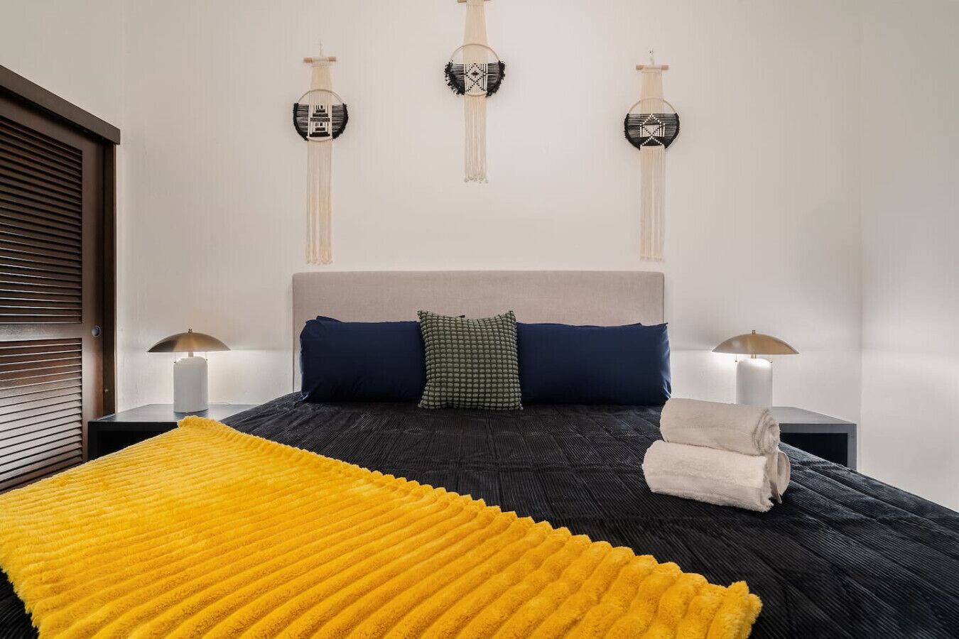 Une chambre moderne avec un grand lit, deux lampes de chevet et trois éléments décoratifs fixés au mur.
