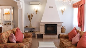 A living room with floral-patterned sofas, a white coffee table, a fireplace, and decorative wall sconces. - Summer Villa With Heated Private Pool (Faro)