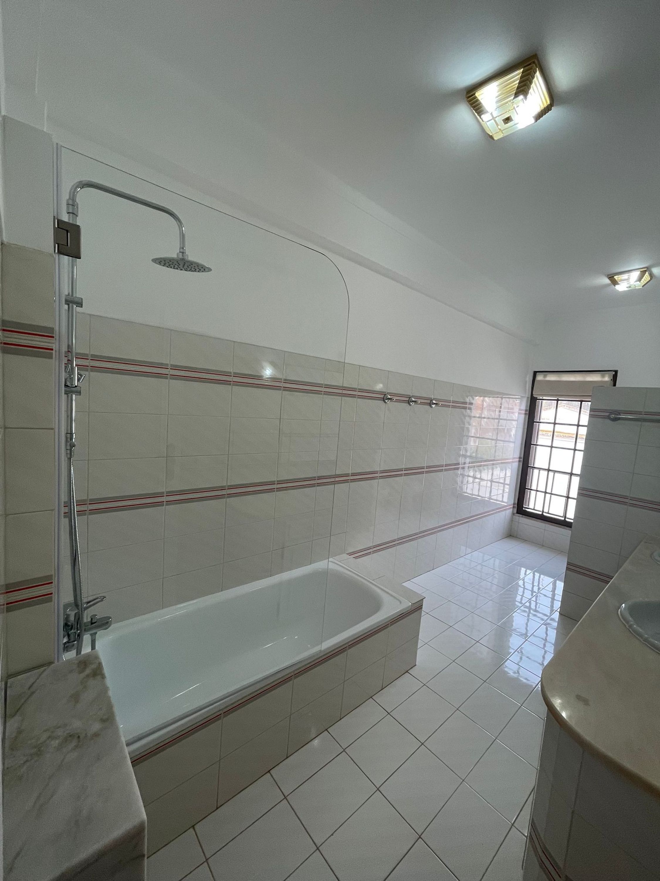 A bathroom with a bathtub, shower, and a window.