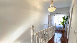 A polished wooden staircase with a white balustrade, a chandelier, and a large window with sheer curtains. - Summer Villa With Heated Private Pool (Faro)