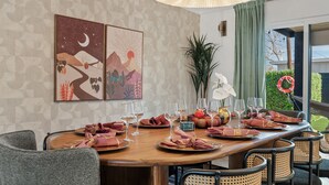 A dining area with a long table set for six, featuring a modern design with geometric wall patterns, a hanging light fixture, and a view of the outdoors. - Old Town | Pool | Spa | Sauna | City of Sunsets (Scottsdale)
