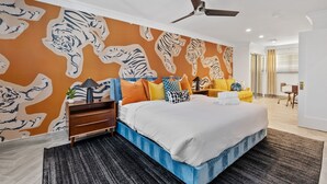 A bedroom with a large bed, a ceiling fan, a nightstand, and a wall with tiger patterns. - Old Town | Pool | Spa | Sauna | City of Sunsets (Scottsdale)