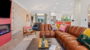 A modern living room with a leather sofa, a flat-screen TV, and a fireplace. - Old Town | Pool | Spa | Sauna | City of Sunsets (Scottsdale)