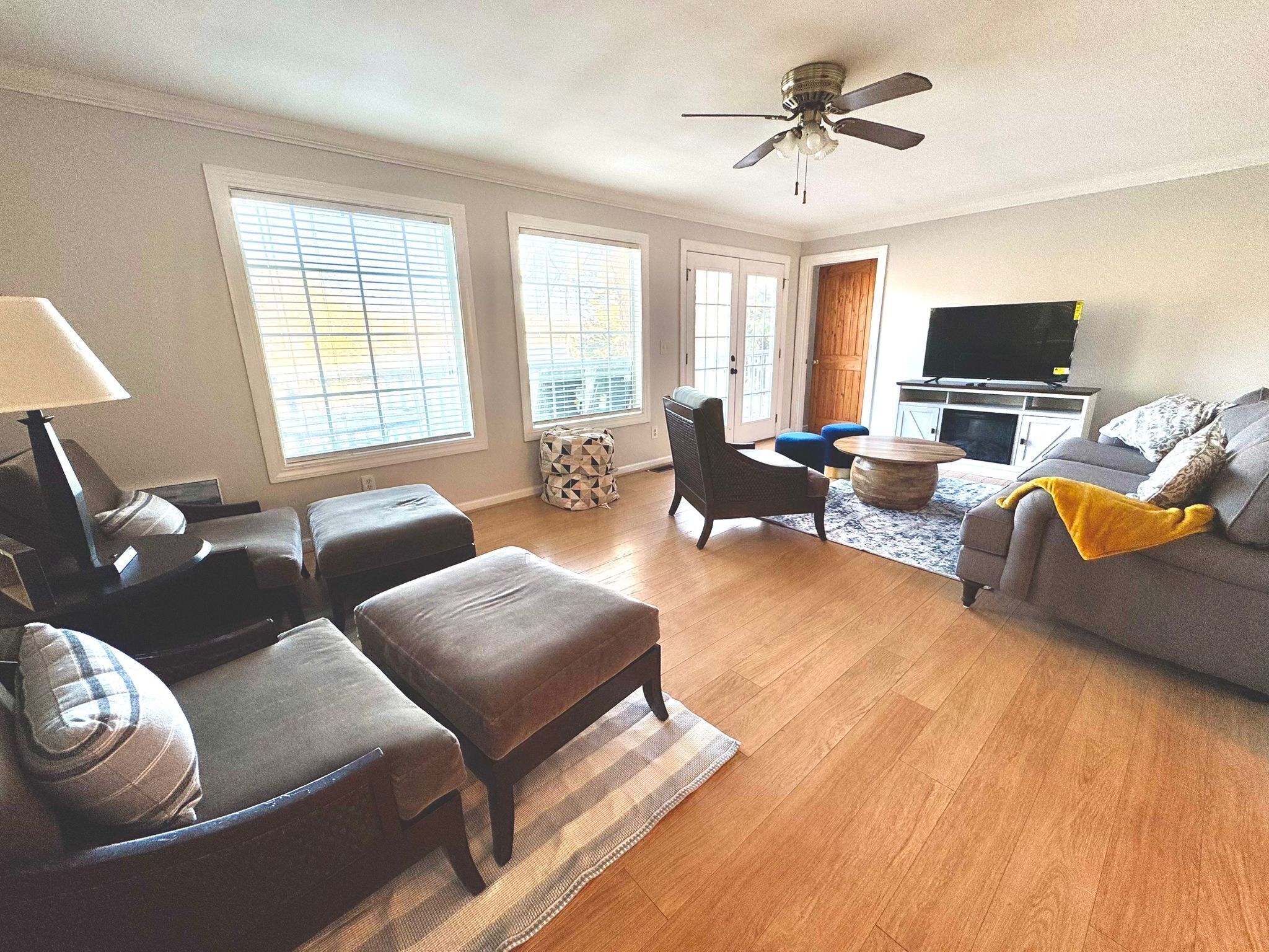 A living room with a sofa, ottomans, a coffee table, and a television.