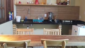 Una cocina compacta con armarios de madera, una encimera negra y una mesa de comedor con sillas.
