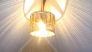 Una habitación acogedora, con poca luz, que tiene una cama, un colgador de lámpara y una pequeña mesa de madera.