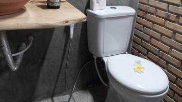A bathroom with a toilet, a sink, a mirror, and a brick wall.