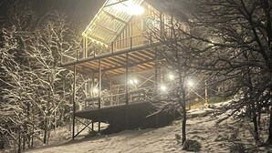 A snow-covered outdoor area with a wooden structure featuring a glass roof and multiple levels.