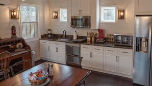 A modern kitchen with white cabinets, stainless steel appliances, and a dining area with a wooden table and chairs.
