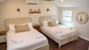 A bedroom with two beds, wooden headboards, a large wall clock, and an air conditioning unit.