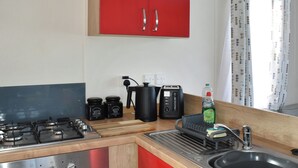Een keuken met een gasfornuis, een spoelbak, een broodrooster en een koffiezetapparaat.