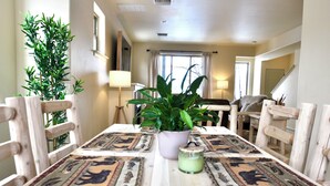 A dining area with a wooden table, chairs, a potted plant, and a candle. - Modern Rustic 3 Bedroom with Pool and Hot tub (Hailey)
