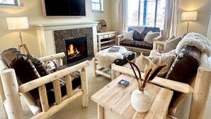 A cozy living room with a fireplace, wooden furniture, and a flat-screen TV. - Modern Rustic 3 Bedroom with Pool and Hot tub (Hailey)