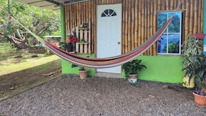 A house with a green exterior, a white door, and a hammock in front. - Hostal Rancho Crustáceo del Pacifico (La Unión)