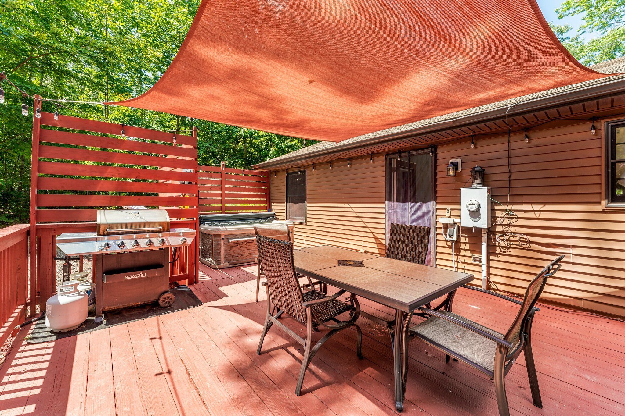 A covered outdoor patio with a grill, table, and chairs.