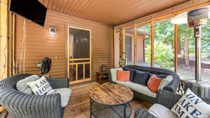 A cozy outdoor seating area with wicker furniture, a round wooden table, and a heater.