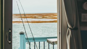 A view from a room with a door leading to a balcony overlooking a body of water.