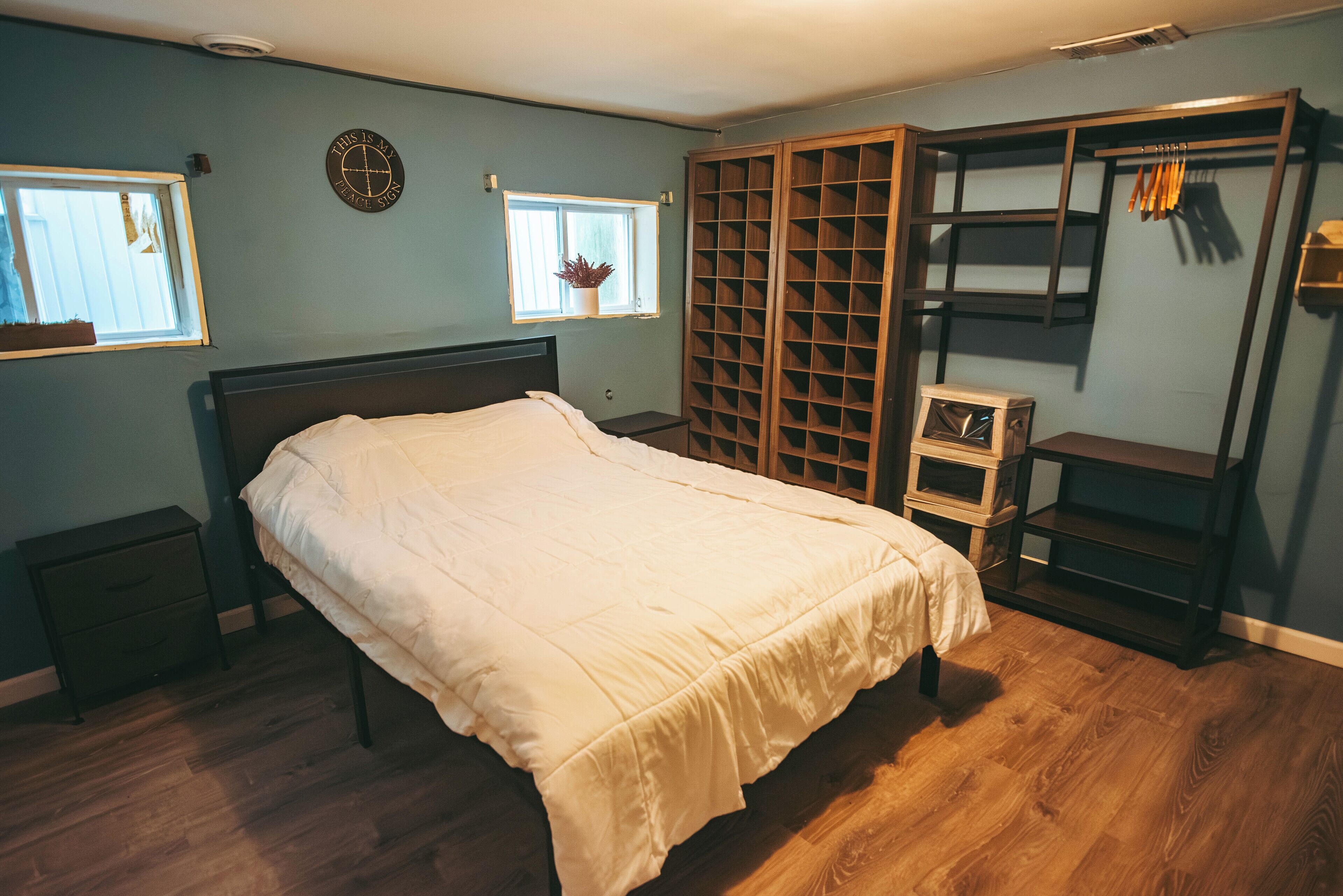 A bedroom with a bed, a wardrobe, a window, and a small table.