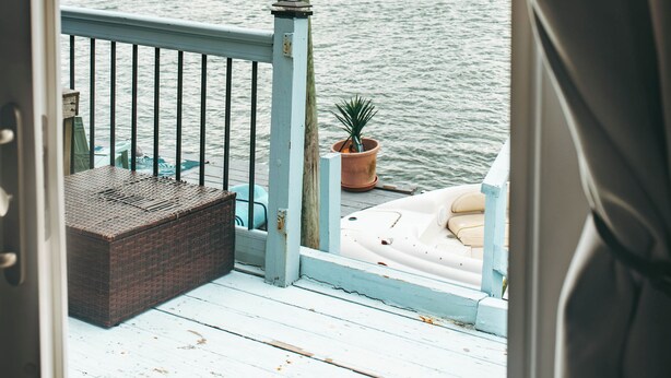 A deck with a railing, a potted plant, and a boat.
