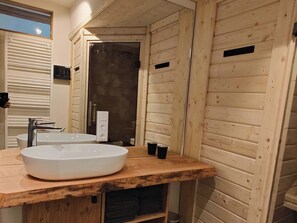 A bathroom with a wooden vanity, a large sink, a mirror, and a shower door. - Exclusive penthouse flat with private sauna and two fireplaces (Großharthau)