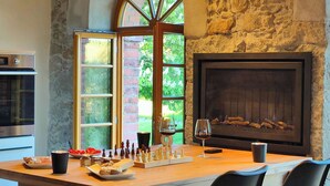 Una cocina con pared de piedra, chimenea y un tablero de ajedrez sobre la encimera.