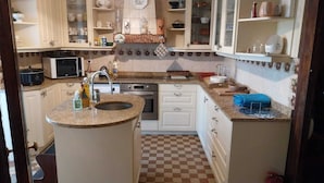 A kitchen with a central island, white cabinets, a microwave, an oven, and a checkered floor. - Large house Loire view + veranda + terrace + garden (Chaumont-sur-Loire)