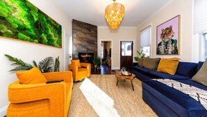 A living room with a sofa, armchair, and a coffee table. There is a painting on the wall and a chandelier. - Central house location! Private yard w/ Firepit, BBQ, 3 Kings, 75" TV, Parking (Columbus)