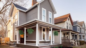 A two-story house with a porch, a chimney, and a front yard. - Central house location! Private yard w/ Firepit, BBQ, 3 Kings, 75" TV, Parking (Columbus)