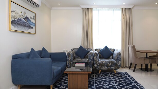 Un salon moderne avec un canapé bleu, un fauteuil à motifs et une table à manger avec des chaises.