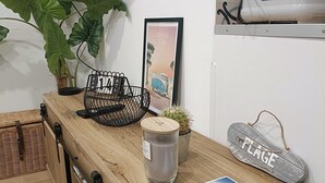 A wooden desk with a framed picture, a small potted plant, a candle, a magazine, and a decorative item labeled "FLAGE". - Apartment 50m from the beach (Saint-Jean-de-Monts)