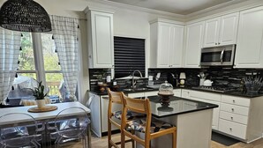A modern kitchen with white cabinetry, a black countertop, and a central island. - Roswell Mini Mansion with Man Cave (Roswell)