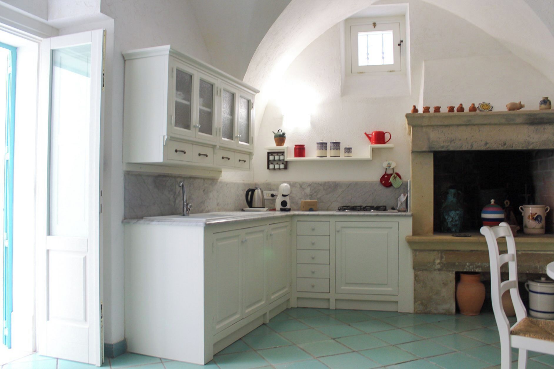A kitchen with white cabinets, a stove, and a tiled floor.