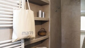 Ein Badezimmer mit Handtuchhalter, Ablagen für Toilettenartikel und einer aufhängbaren Tasche.