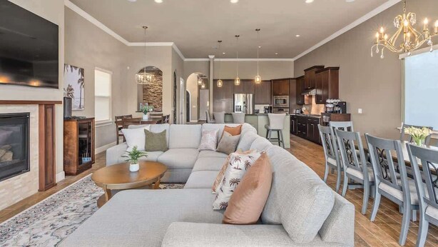 A spacious living room with a large sectional sofa, a fireplace, and a dining area with a chandelier.