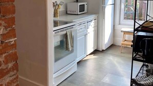 A kitchen with white cabinets, a microwave, a refrigerator, and a wooden floor. - Pethick's Lookout Suite: Family-Friendly Apartment (Charlottetown)