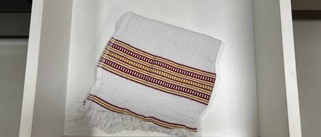 A framed textile with a geometric pattern, displayed in a white, minimalist setting.