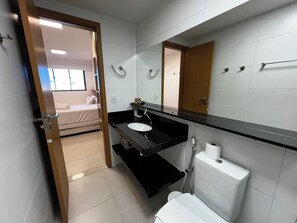 A modern bathroom with a black countertop, white sink, and a large mirror. - STUDIO DESIGN 3 - APTO 915 (Maceio)