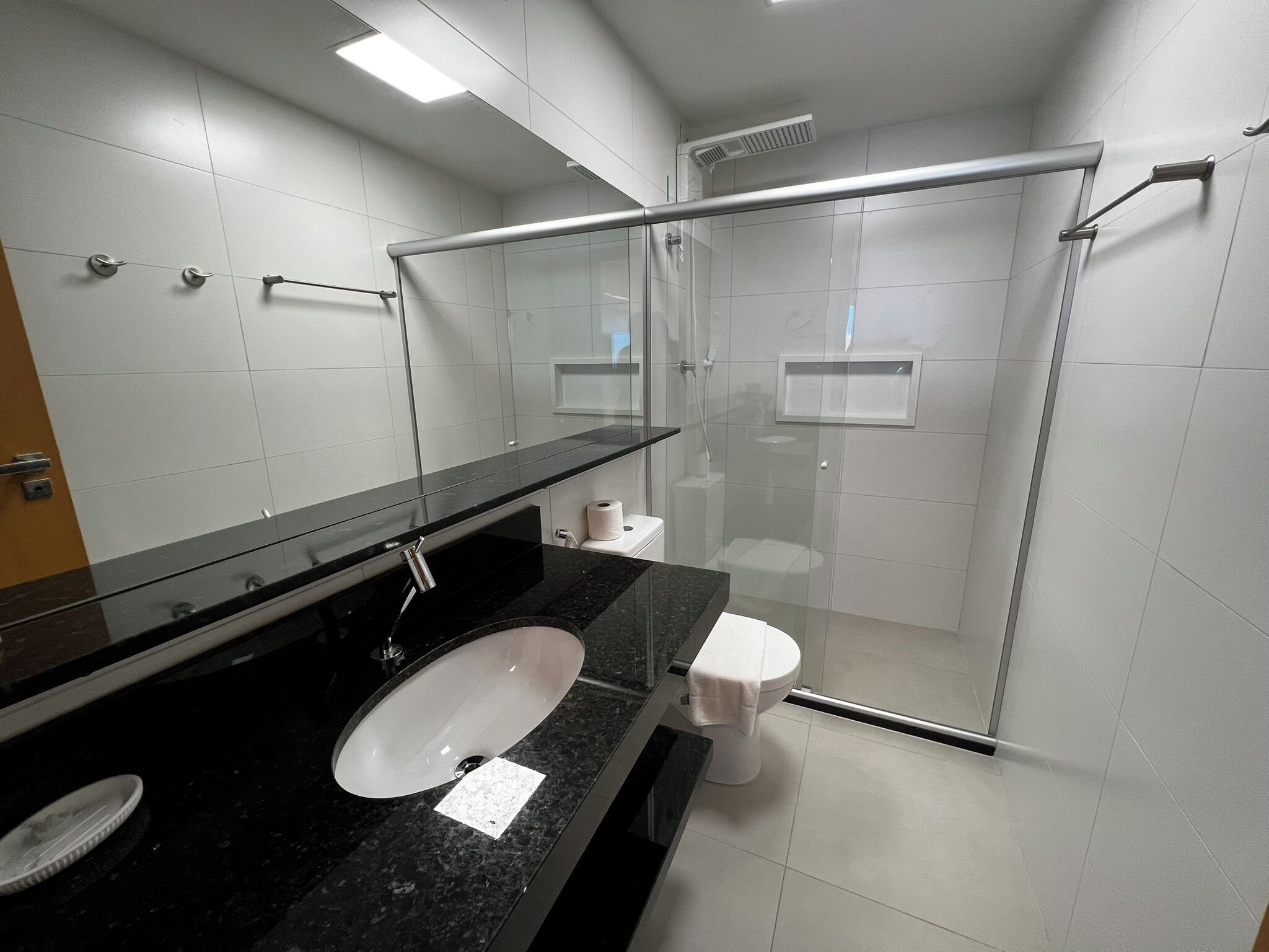 Un baño moderno con cabina de ducha de vidrio, un lavabo con espejo y un inodoro.