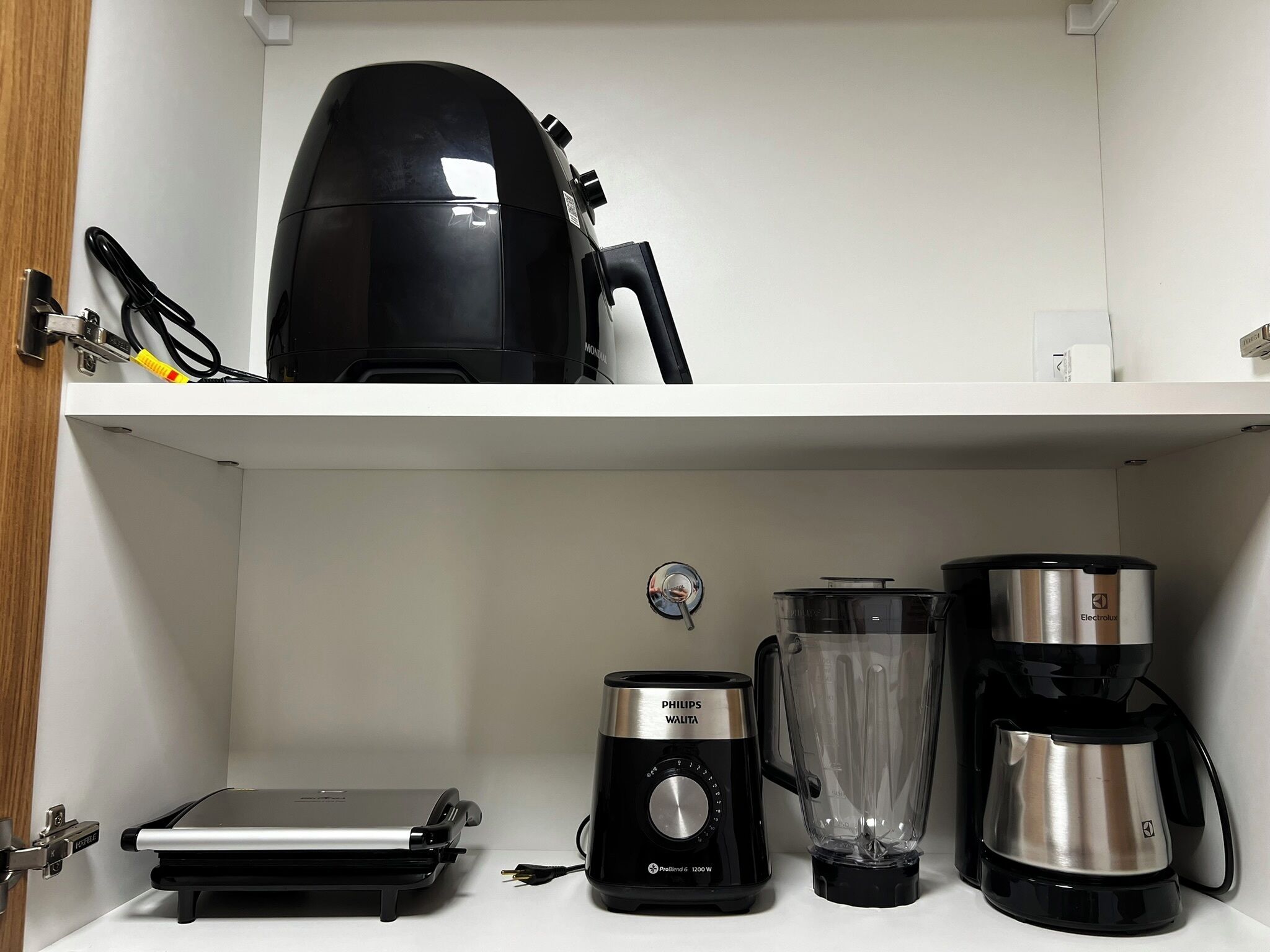 Ett kök med en kaffebryggare, en mixer och en liten köksmaskin på bänkskivan.