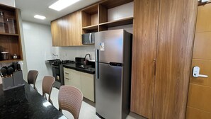 Eine moderne Küche mit Holzausstattung, einem Edelstahlkühlschrank, einer Mikrowelle und einem Gasherd.