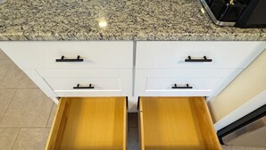 A kitchen with white cabinets, granite countertops, and two wooden drawers. - Charming Lake Town Home with WiFi (Inverness)