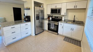 A modern kitchen with white cabinets, a stainless steel refrigerator, a microwave, and an oven. - Charming Lake Town Home with WiFi (Inverness)