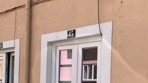 Un bâtiment à la façade beige, une porte blanche portant le numéro 45 et une fenêtre dont l’intérieur est rose.