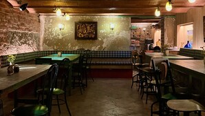 Een restaurant met gedempt licht, zichtbare bakstenen muren, een lange bar en verschillende ruimtes.