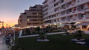 Un hotel de varios pisos con balcones, mobiliario exterior y un césped bien cuidado.